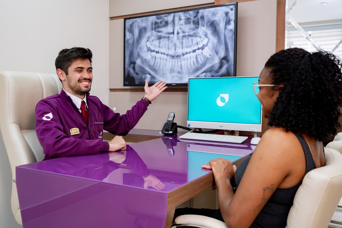 Dentista da Oral Unic Alvorada apresentando o planejamento do protocolo de implante a partir do raio-X panorâmico