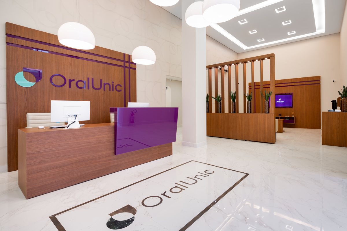 Recepção da Oral Unic Alvorada, com logo da marca no piso